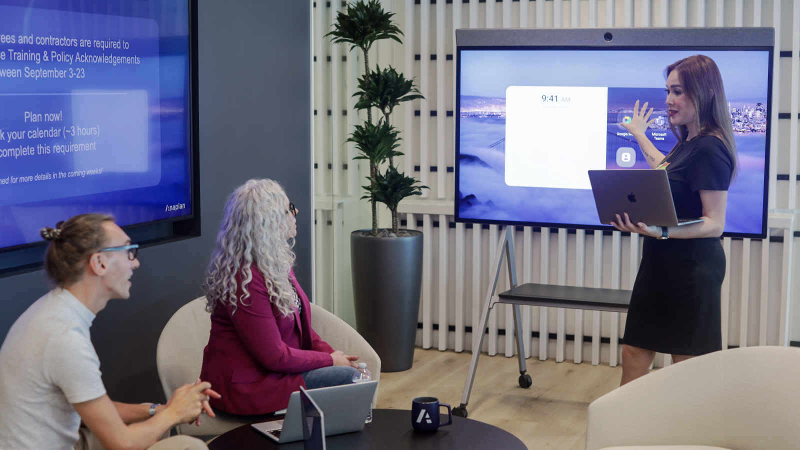 Anaplan Careers Be Connected Resource Tile One Anaplan employee presenting to two others in a relaxed setting